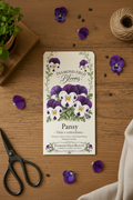 Diamond Field Blooms Pansy seed packet flat lay on wooden table with purple pansy petals, twine and scissors